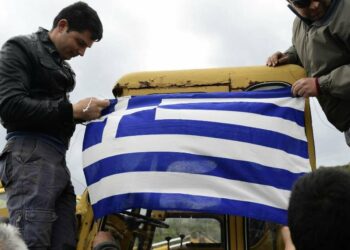 Local residents hang the Greek flag at a roadblock in Karava, on the northeastern Aegean island of Lesbos, Greece, Thursday, Feb. 27, 2020. Greece's government hoped to defuse tensions after protests over plans for new migrant camps on two of its islands Wednesday turned into violent clashes between police and local residents, some armed with Molotov cocktails and shotguns.(AP Photo/Michael Varaklas)