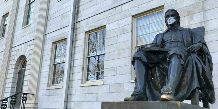 La statua di John Harvard con la mascherina anti-Coronavirus (Foto LaPresse)