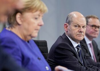 Federal Finance Minister Olaf Scholz, second right, looks at German Chancellor Angela Merkel, during a news conference in Berlin, Thursday, Nov. 18, 2021. German lawmakers have approved new measures to rein in record coronavirus infections after the head of Germany’s disease control agency warned the country could face a “really terrible Christmas.” The measures passed in the Bundestag on Thursday includes requirements for employees to prove they are vaccinated, recovered from COVID-19 or have tested negative for the virus in order to access communal workplaces. (Michael Kappeler, Pool via AP)